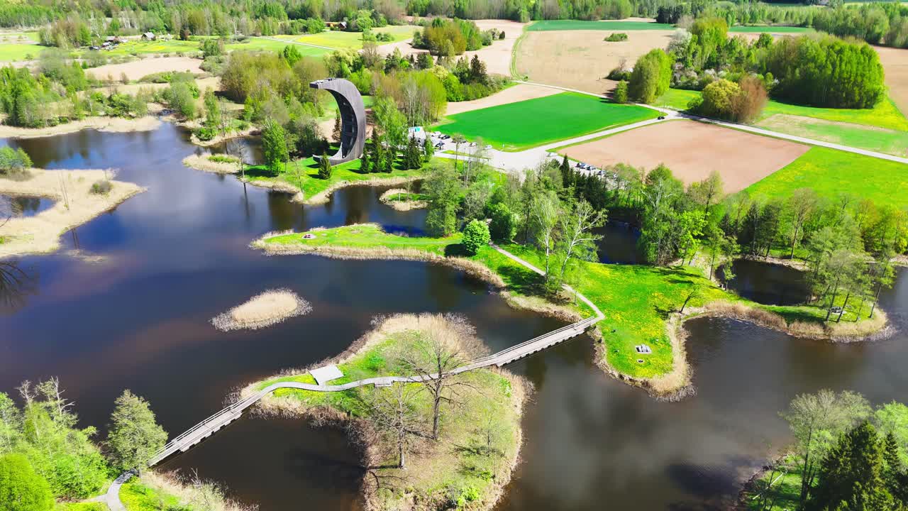 Biržai Regional Park, Lithuania - The Crescent-shaped Kirkilai Observation Tower Provides a View of the Karst Lakes, Meandering Bridges, and Verdant Vegetation - Drone Flying Forward