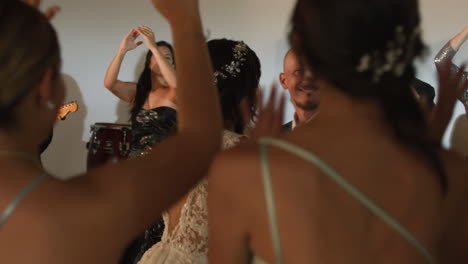 clip of an elegant party where women in formal dresses enjoy live music. a band can be seen livening up the event.