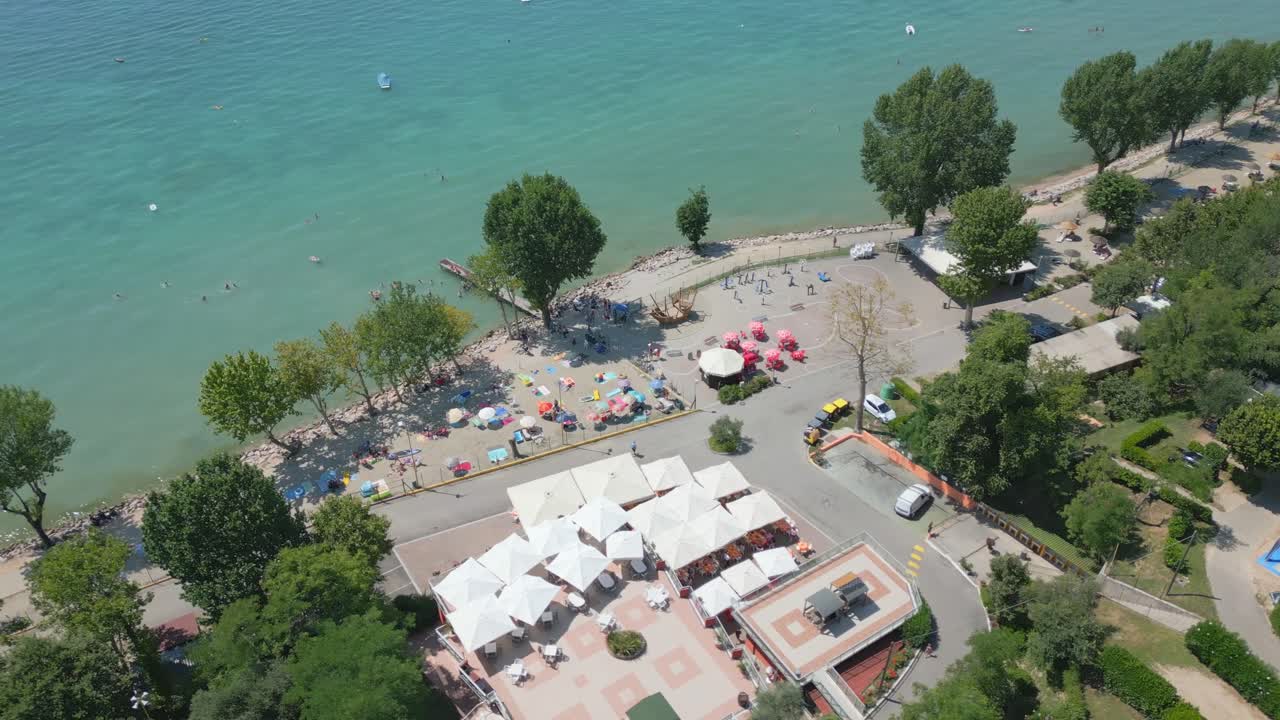 Droonikierto Gardajärven hiekkarannalla, Italiassa, turistien nauttiessa lomastaan.
