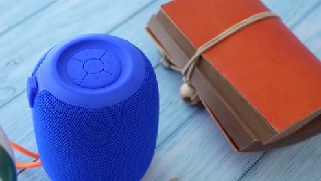 blue portable bluetooth speaker and journal on wooden surface