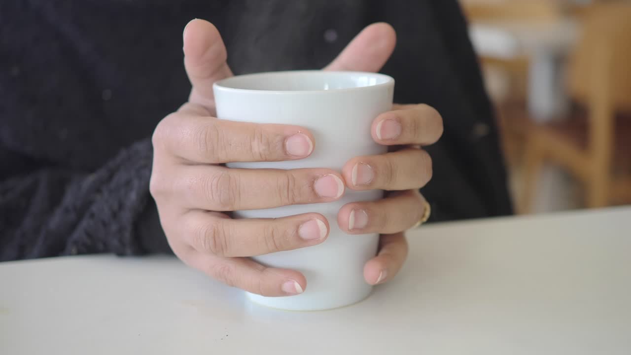 Primo piano di mani che tengono una tazza fumante