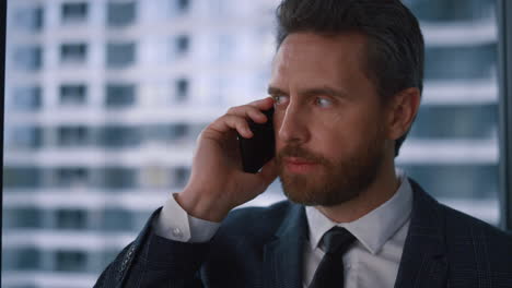 Un-Hombre-De-Negocios-Jefe-Adulto-Serio-Hablando-Por-Teléfono-Llamando-A-Un-Móvil-En-Una-Oficina-Moderna.