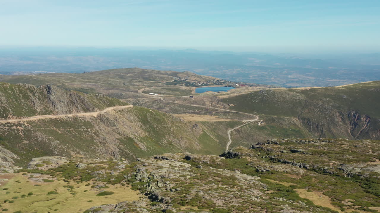 Aerial shot flying forward through Serra da Estrela Natural Park, mountains and lagoon background