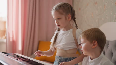 sister shows piano chords to brother and asks to repeat