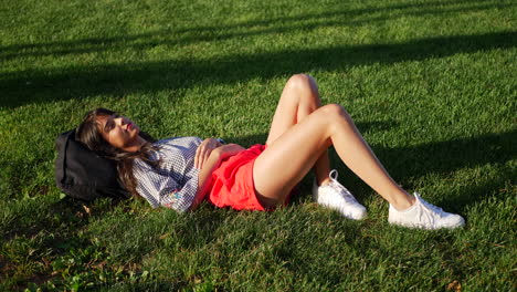 Beautiful-young-hispanic-woman-resting-and-daydreaming-in-a-grass-public-park-field-as-she-watches-the-clouds