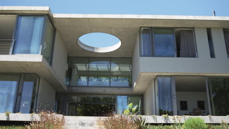 una casa moderna cuenta con grandes ventanas de vidrio y una abertura circular distintiva