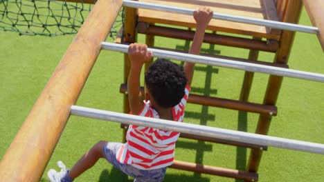 high angle view of african american schoolboy playing on horizontal ladder in school playground 4k