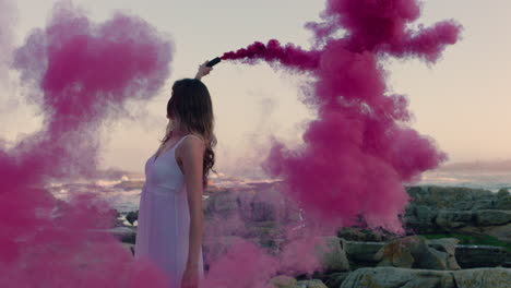 beautiful woman waving pink smoke bomb dancing on beach at sunrise celebrating creative freedom