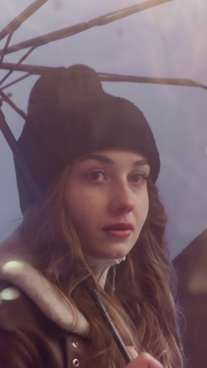Close shot of female holding umbrella walking past cafe, looking through glass window on cold overcast day, wearing black knit cap, brown shearling jacket, with rainy atmosphere outside