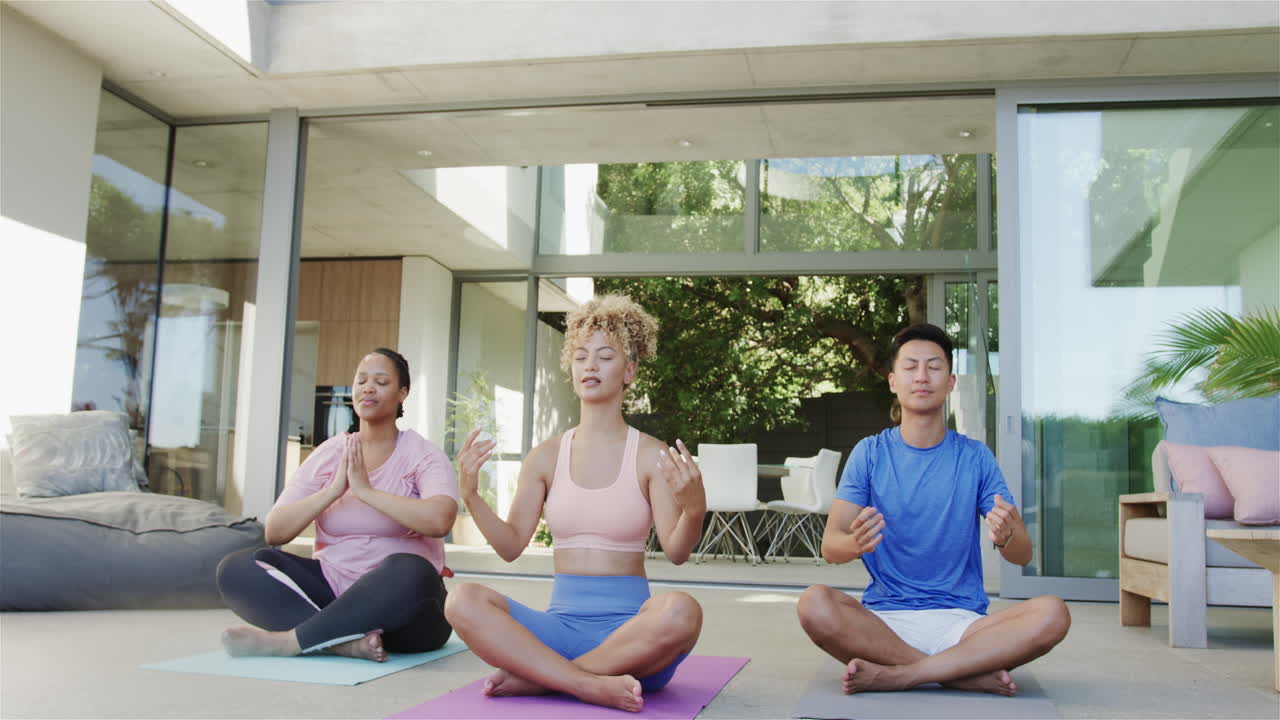 mujeres jóvenes de dos razas y un hombre asiático meditan en casa