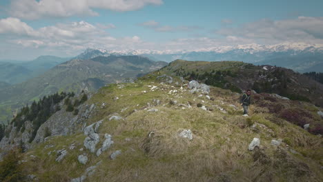 Disparo-De-Un-Dron-De-Un-Excursionista-Que-Comienza-A-Caminar-Con-Bastones-De-Senderismo-Desde-La-Cima-De-La-Montaña-Hacia-El-Valle