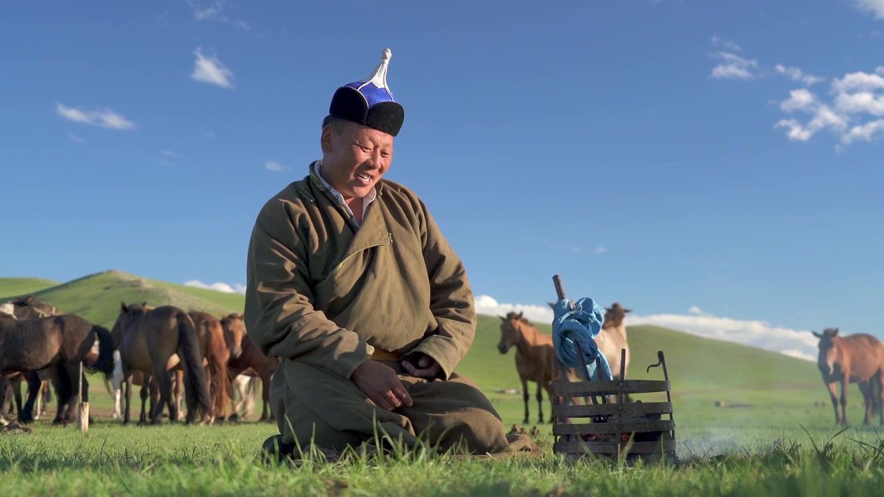 Mongolsk gjeter sitter ved et lite bål på steppen.