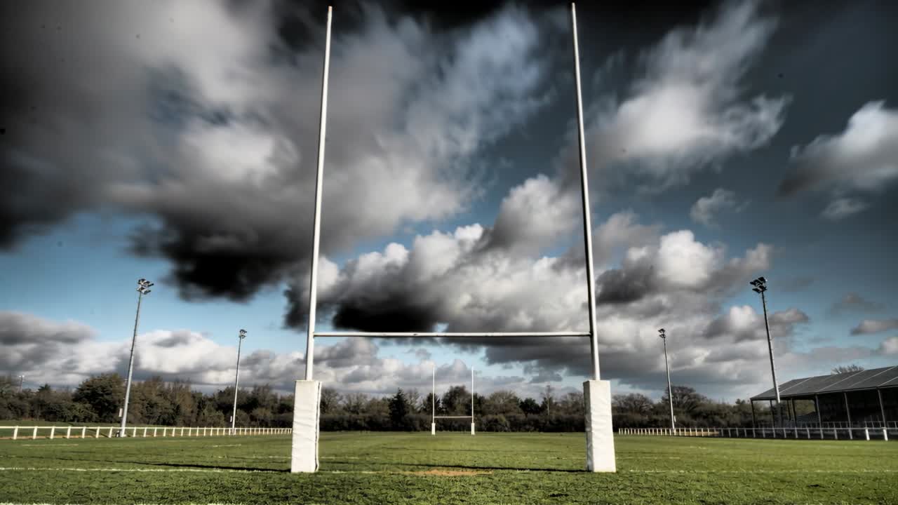 Framing rugby posts, camera pushing, posts rising while clouds racing across club field for drama