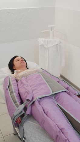 woman making pressotherapy procedure treatment in a beauty salon lying on medical bed and relaxing