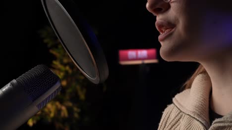 mujer cantando en un micrófono en un estudio de grabación