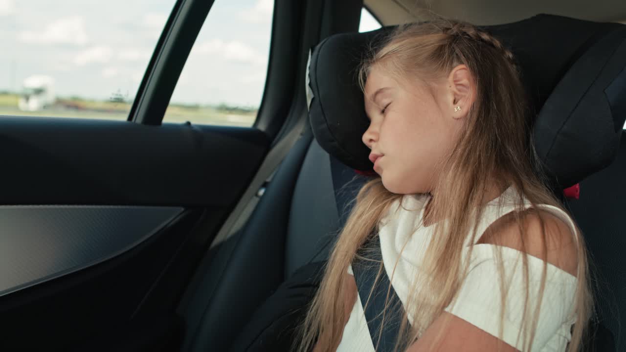 niña caucásica durmiendo mientras viaja en el coche.