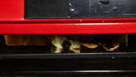 sandwiches are being cooked inside sandwich cooking machine. melted cheese.