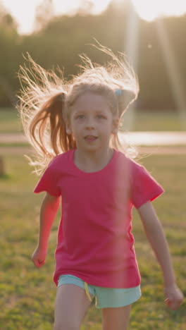funny blonde girl with tongue out runs along large playground at sunset slow motion. active child plays in city park. enjoying summer season