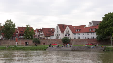 people hanging out on donaustufen by the danube riverside with ulm city wall in germany