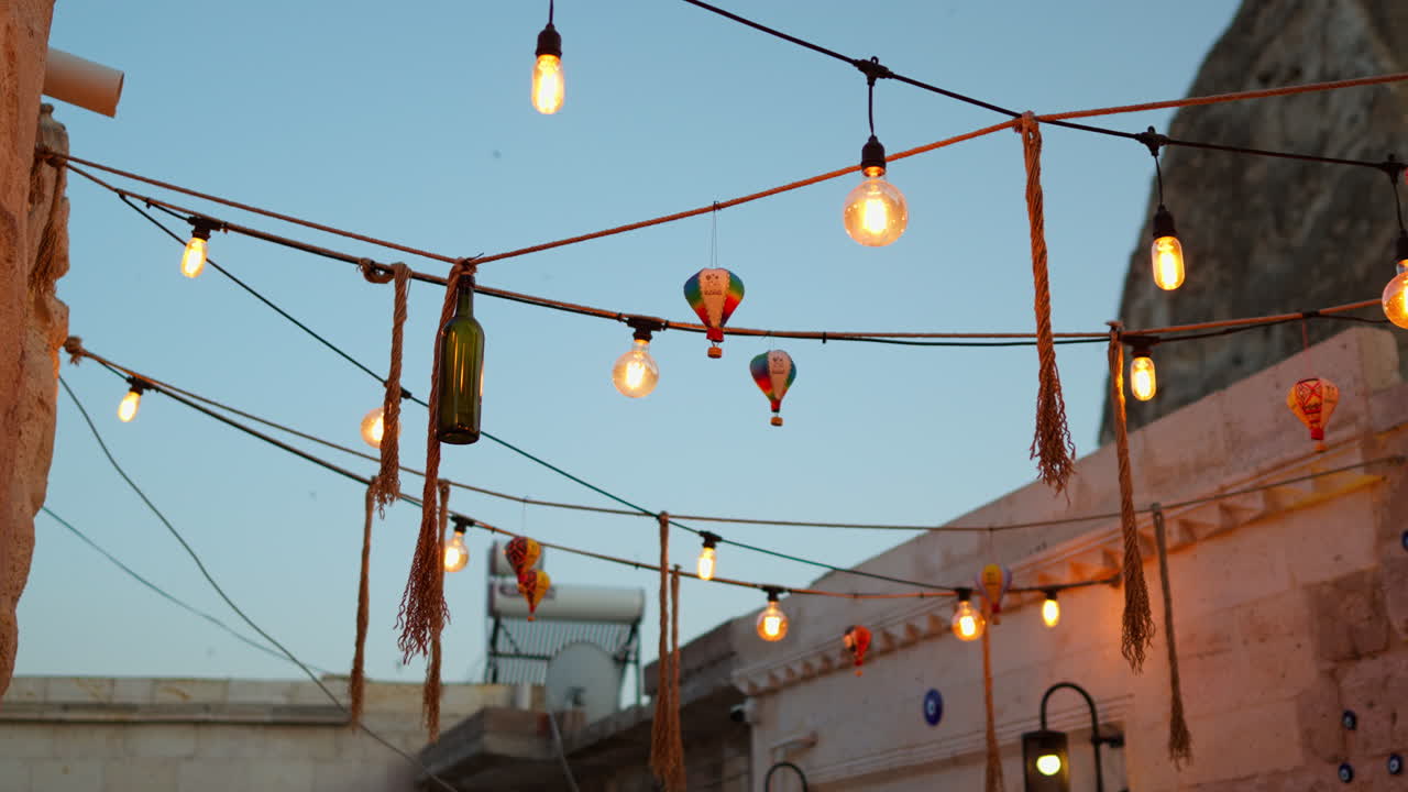 A charming alley in Cappadocia with string lights, balloon decorations, and Turkish vibes under a blue sky.