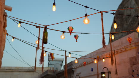 a charming alley in cappadocia with string lights, balloon decorations, and turkish vibes under a blue sky.