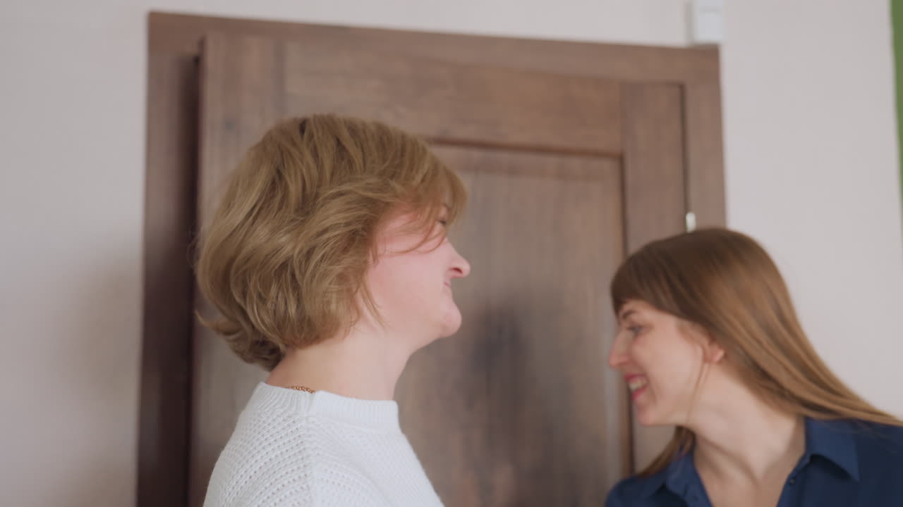 Back view of woman entering room as therapist opens wooden door with cheerful smile to welcome client for therapy session, showing warm professional connection and positive mental health environment