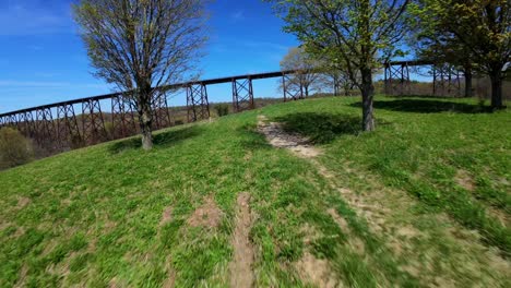 A-low-angle-aerial-view-with-an-FPV-drone-flying-towards-the-Moodna-Viaduct-in-Salisbury-Mills,-NY-on-a-sunny-day