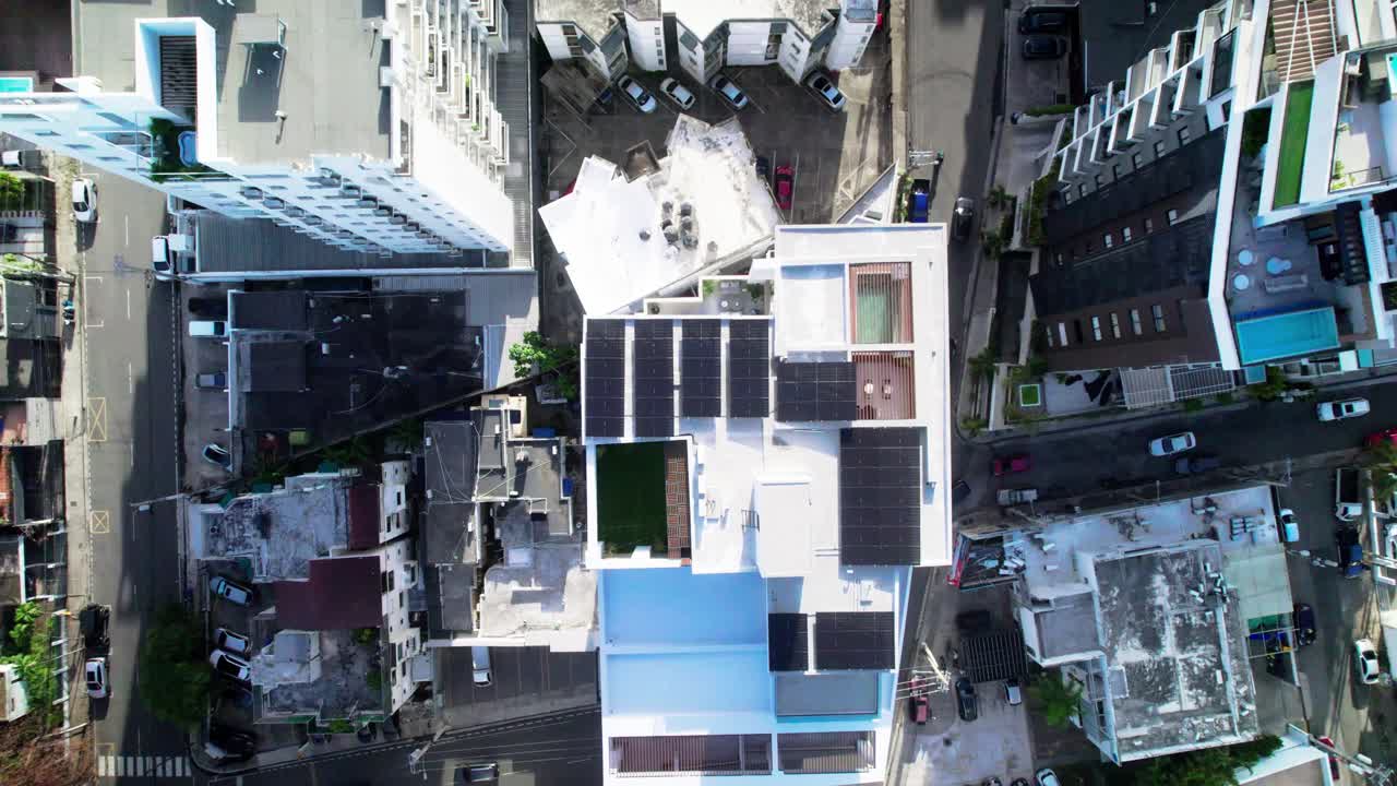 Zenithal zoom out drone shot revealing solar panels installed on an urban building rooftop, showcasing clean energy integration