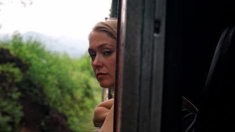 a captivating moment inside the ella-kandy train in sri lanka, where a woman gazes out of the window, taking in the lush, green landscape.
