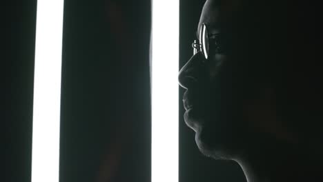 man posing in dark studio with fluorescent lamps