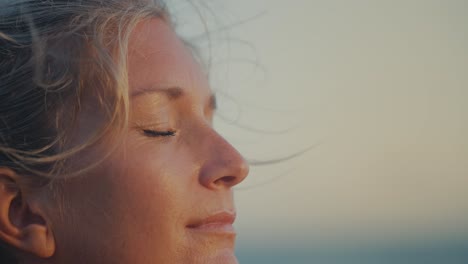 close up of woman face meditating during yoga session, breeze in hair