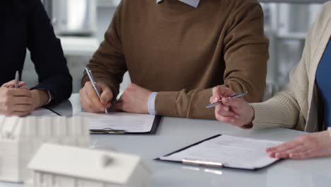 camera focuses hands of business people writing on documents on the table