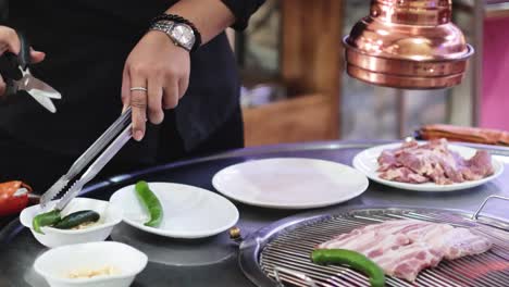 chef grilling meat and vegetables on a stove