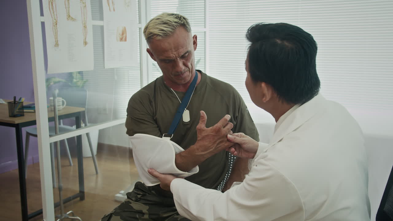 Therapist Examining Injured Arm of Male Soldier at Hospital