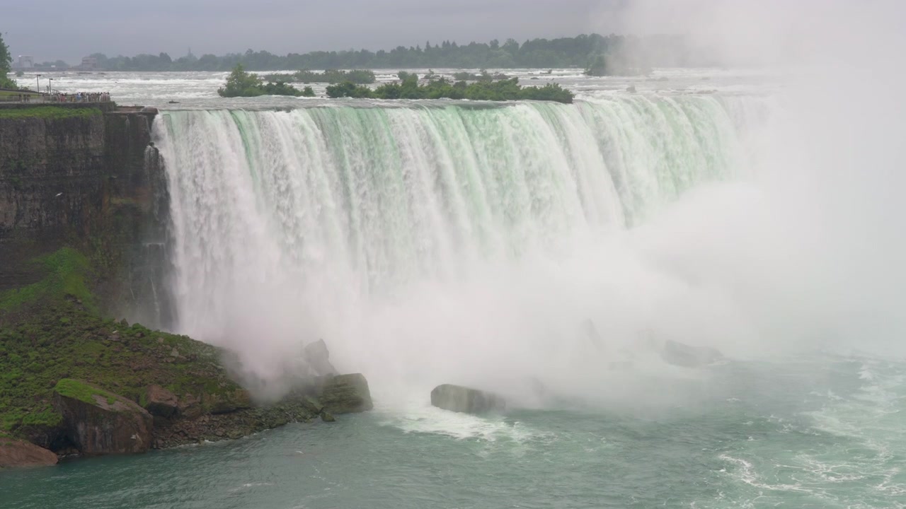 Woda z hukiem spada z Wodospadu Horseshoe do rzeki Niagara, podczas gdy unosi się mgła, a ptaki latają u podnóża. Ujęcie statyczne