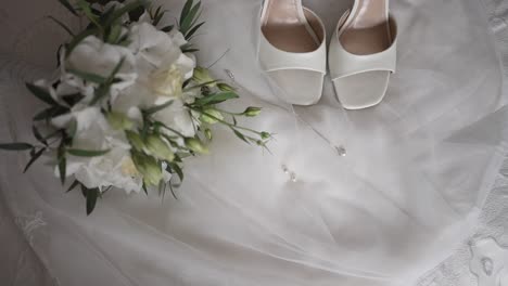 white bridal shoes, necklace, and fresh bouquet on satin