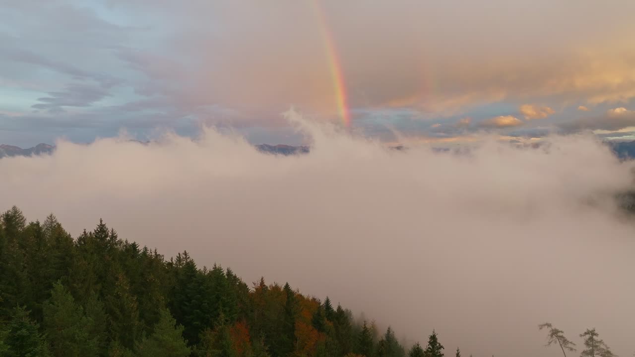 Rainbow above the clouds during sunset, dreamy aerial shot