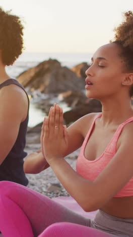 biracial couple practices yoga outdoors at sunset