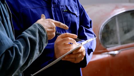 two mechanics writing on clipboard 4k