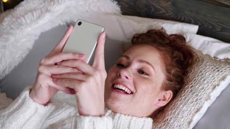 girl with mobile phone spending christmas time in bed