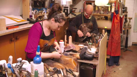 workers in bespoke shoemaker glueing together leather