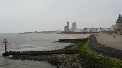 antena larga aproximación ascendente a la playa de la ciudad con pocas personas caminando y un paseo marítimo de vlissingen, zelanda, países bajos