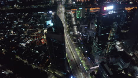 Tiro-De-Inclinación-Aérea-Después-De-Un-Intenso-Tráfico-En-Una-Carretera-De-Varios-Carriles-A-Través-Del-Centro-De-Yakarta-Por-La-Noche