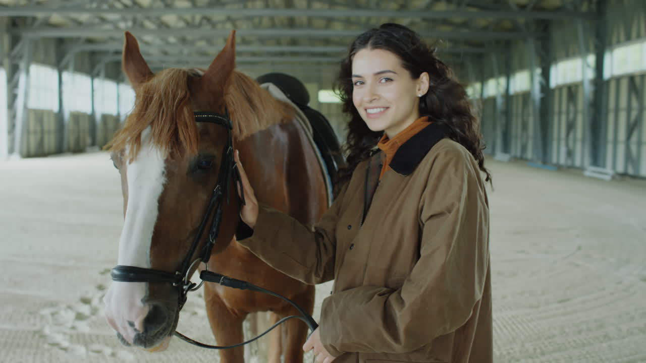 Happy Woman Posing with Chestnut Horse in Riding Arena