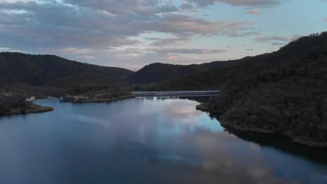 aerial orbit over mountain lake with a dam colorful sunset colors forest trees