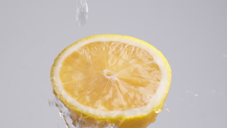 slow motion macro shot of flowing water from lemon slice on white background