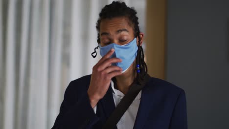 portrait of mixed race man with dreadlocks wearing blue face mask