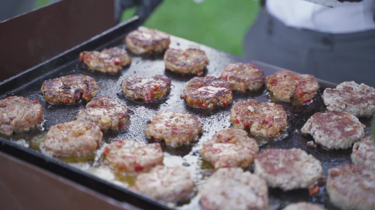 야외 바비큐 공간에서 요리되고 있는 많은 버거를 가까이서 보세요