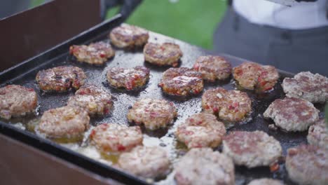 close up of many burgers being cooked on an outside bbq area