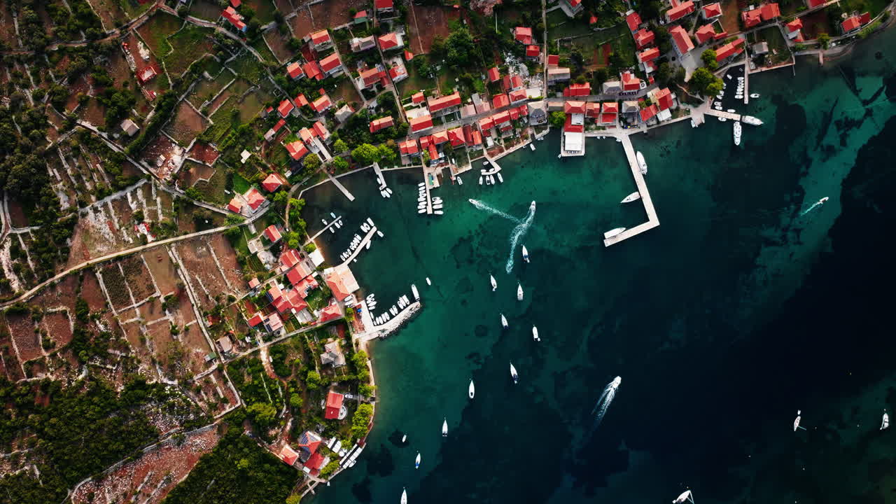 Bird's eye view top down static establishing shot of Ilovik island Croatia coastline and village homes
